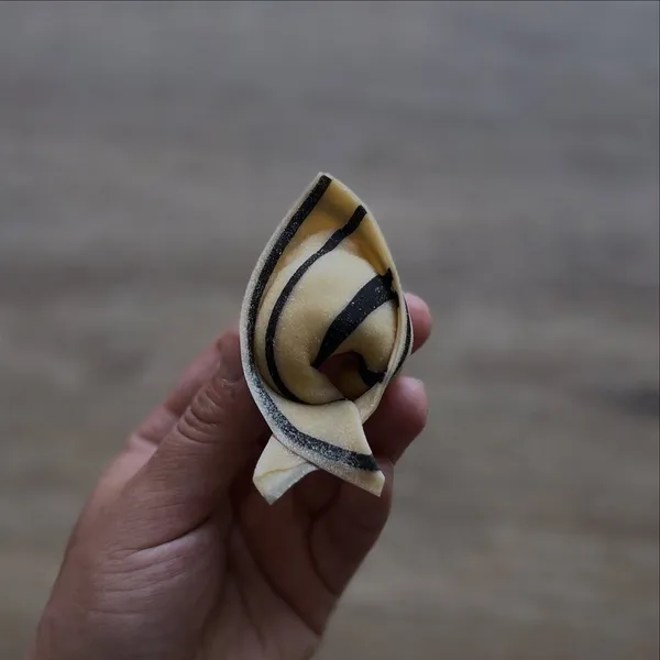 Tortellini con diseño rayado negro y dorado